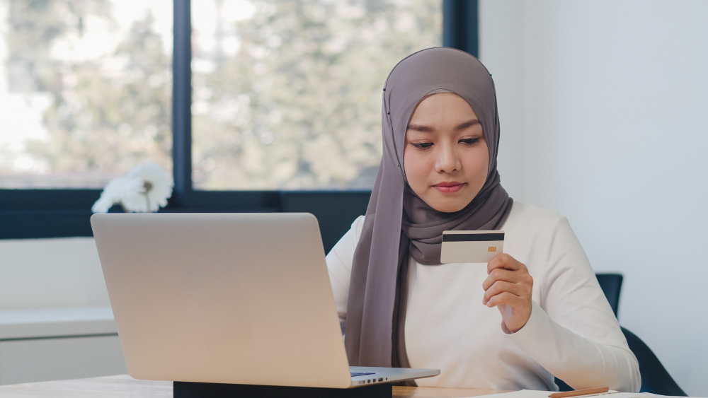 Woman keying in her credit card details onto her laptop computer