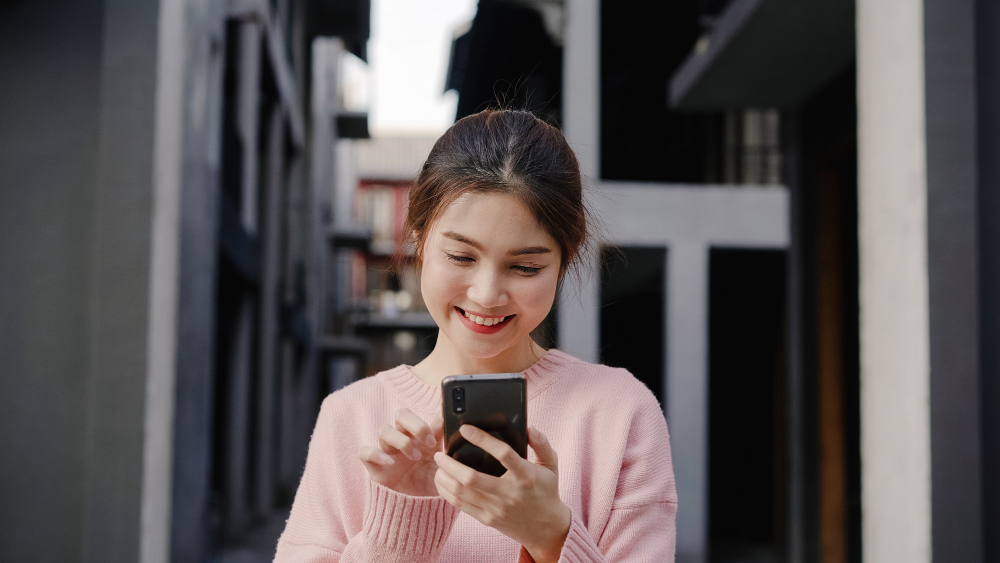 Young woman happily using her smartphone