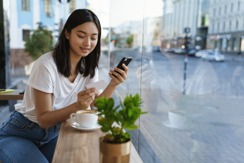 Woman using her smartphone beside a cafe window