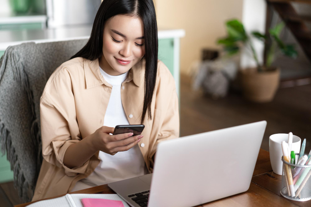 Woman using her phone and laptop